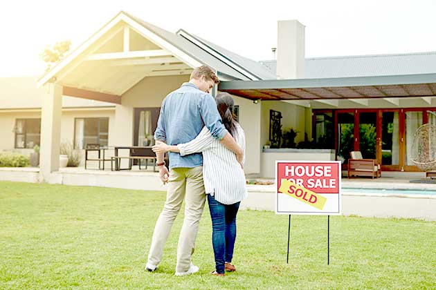 couple on lawn in front of newly purchased home discussing home equity
