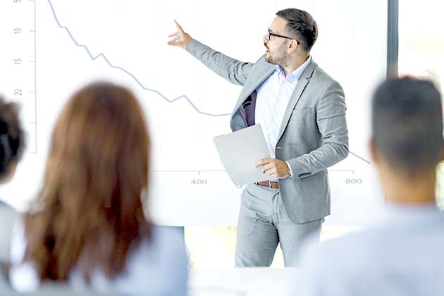 Analyst discussing performance using line graph visual for presentation in conference room.